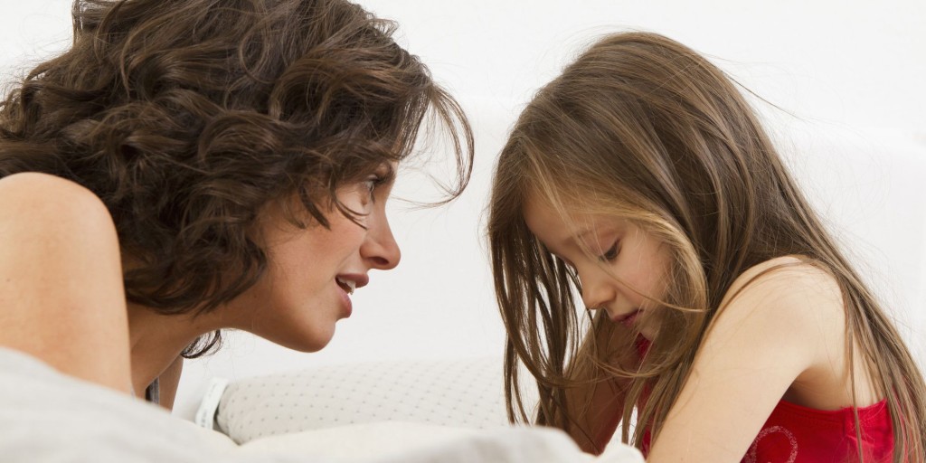 Mother and daughter talking on bed
