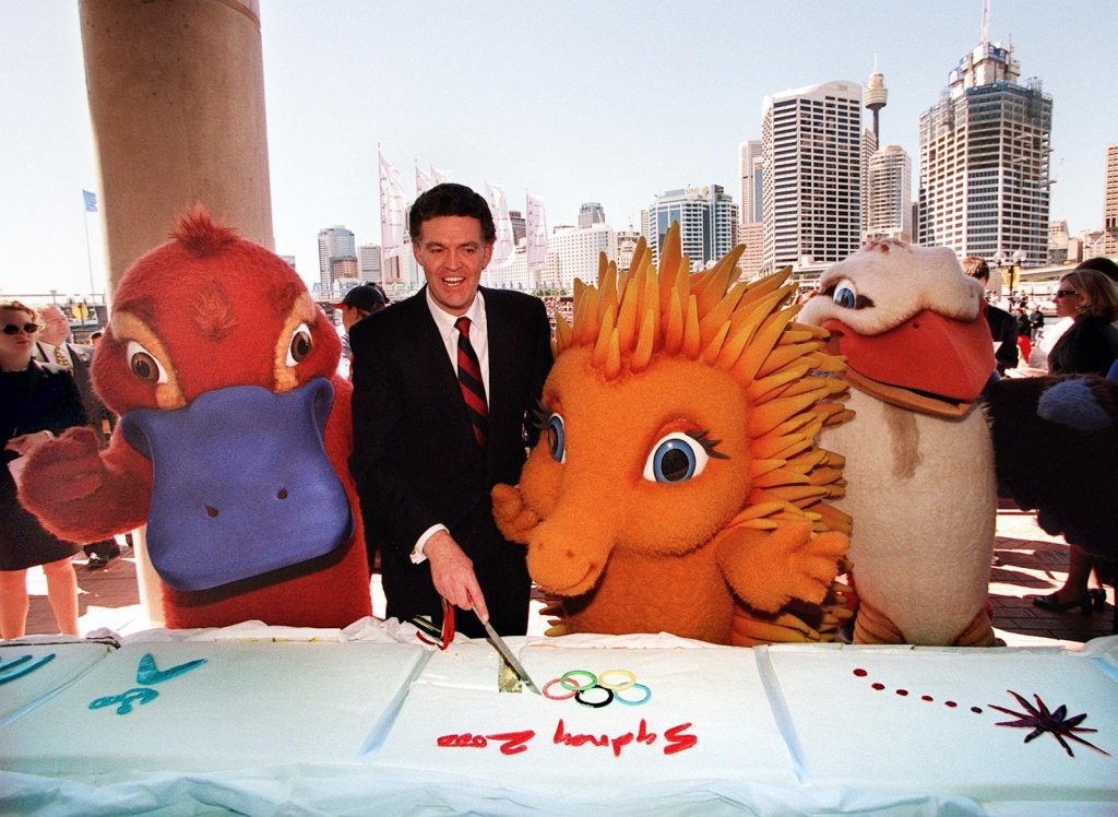 Michael Knight (2nd L), Minister for the Olympics, cuts a portion of the world's longest Olympic cake with Sydney 2000 mascots "Syd" the platypus (L), "Millie" the euchidna (2nd R) and "Ollie" the kookaburra (R) by Sydney Harbour 15 September. The 16-meter-long (48-feet) cake, representing the 16-days of the Sydney 2000 Olympics, marks the two-year countdown to the opening ceremony on 15 September, 2000. AFP PHOTO/Torsten BLACKWOOD