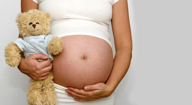 Mujer embarazada con un juguete de su bebé