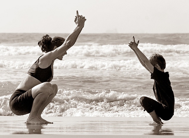 Madre e hijo practicando yoga en la playa