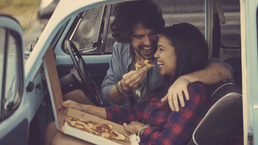 Pareja en un auto comiendo pizza