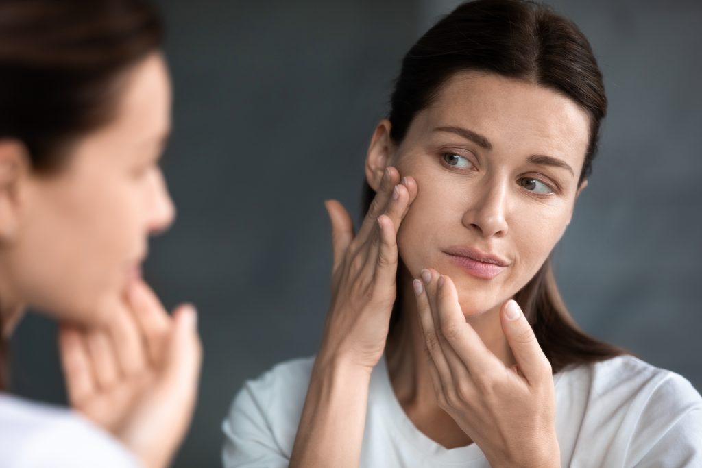 Close Up Unhappy Woman Looking At Acne Spots In Mirror